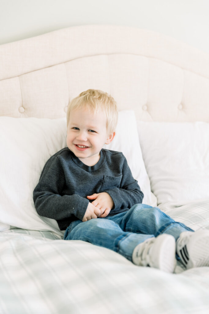 Getting the toddler involved by sitting on the bed and smiling 