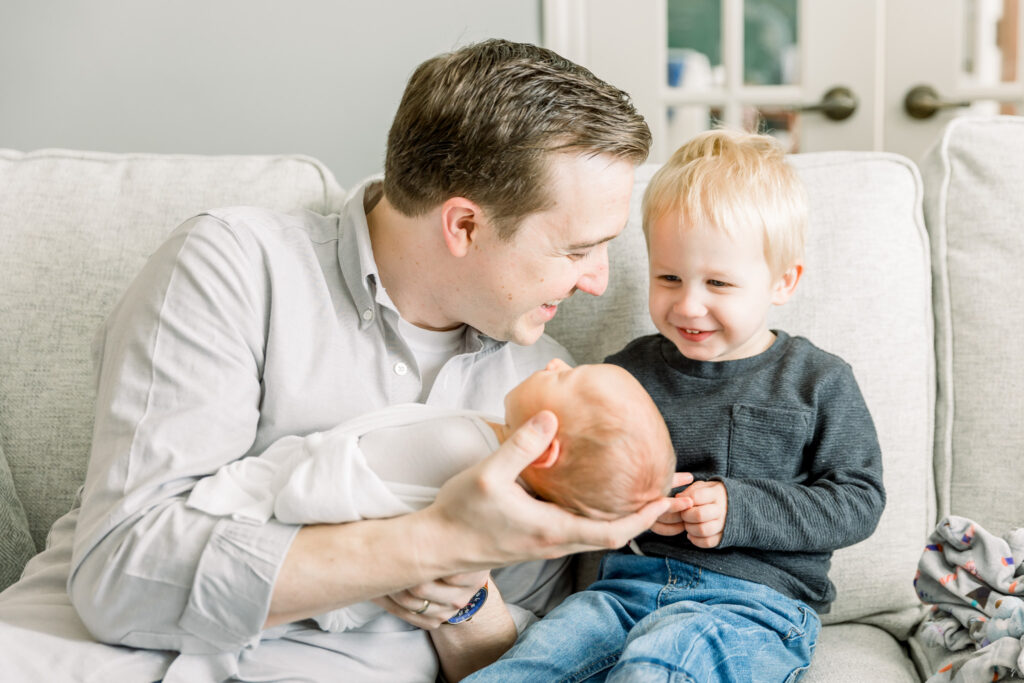 Toddler smiling while Dad holds newborn in family home in Wexford Pa