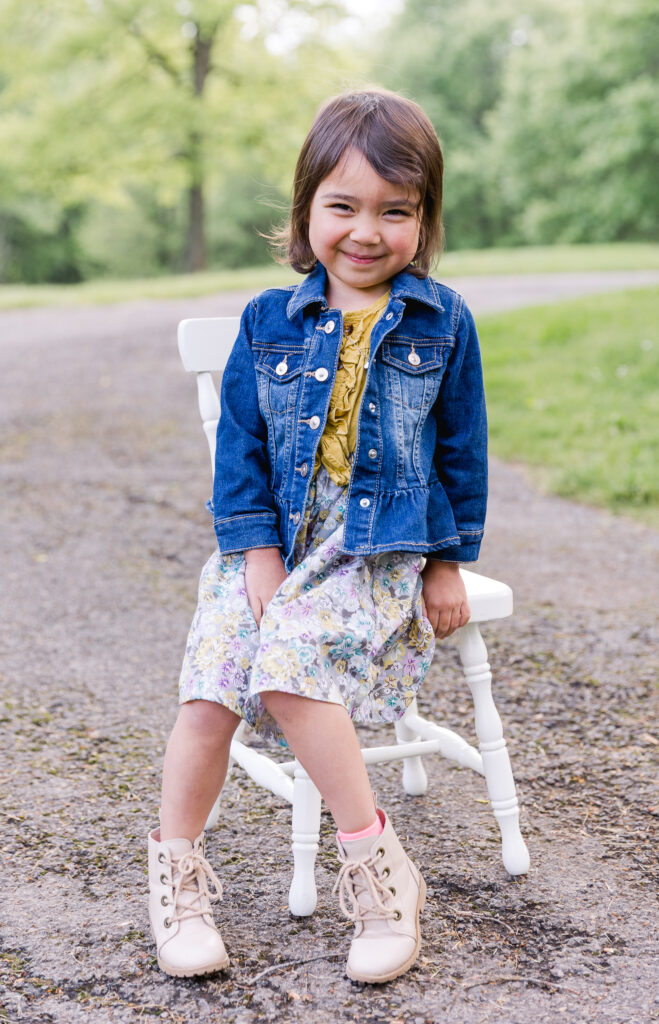 spring family photograph of girl sitting on chair at park for family session