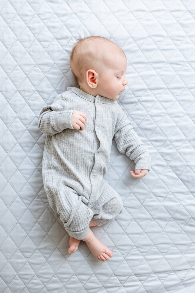 Full body image of newborn sleeping on bed