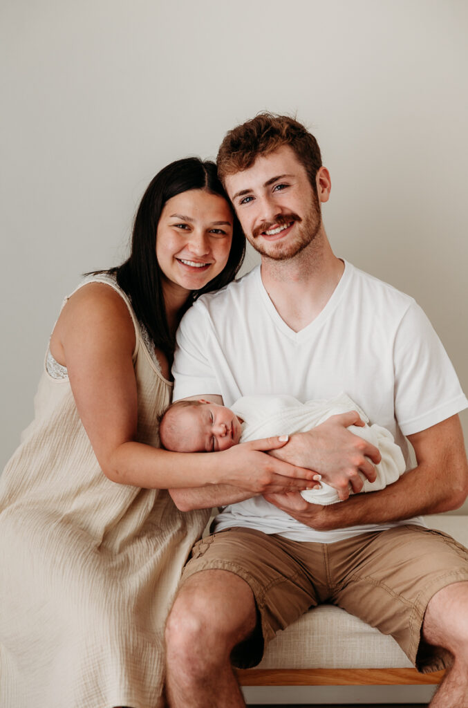 In studio newborn session setup with LED light and cozy family snuggle on bench