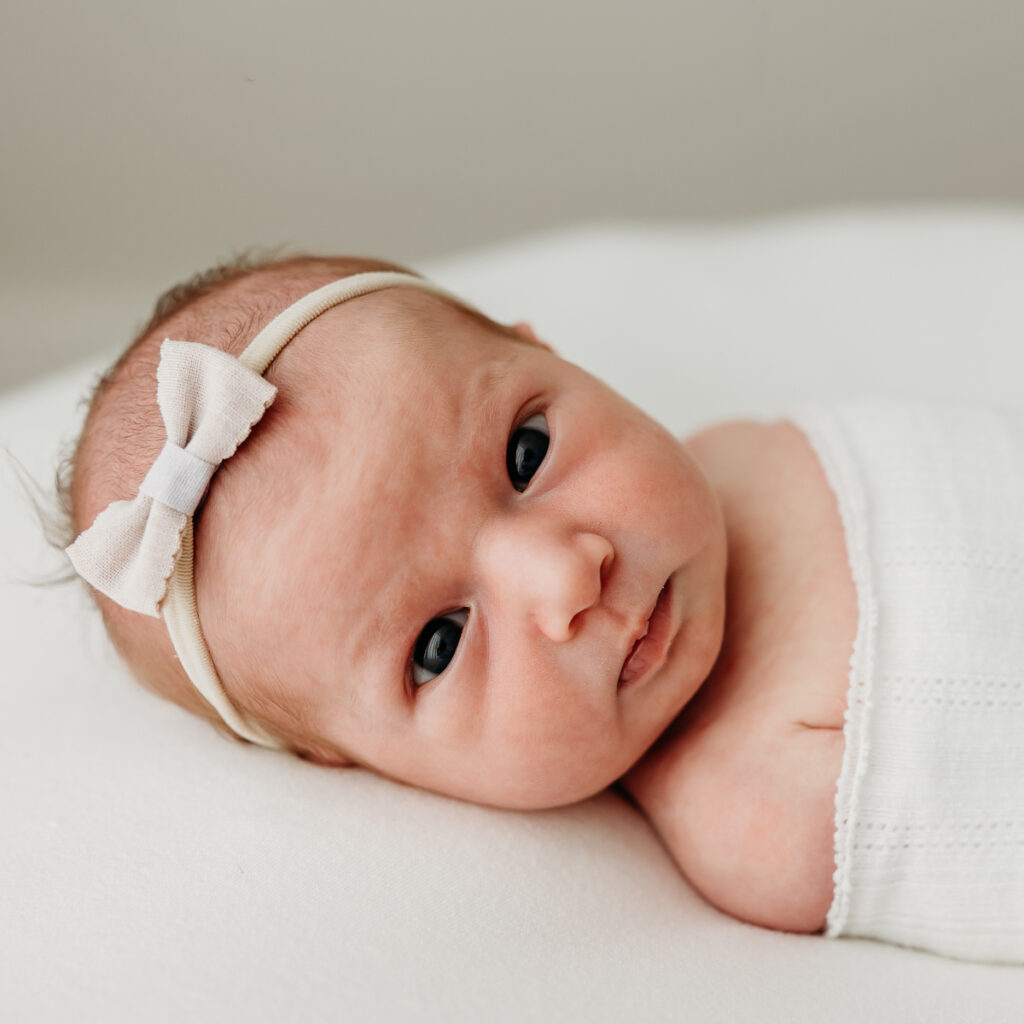 Close up image of newborn on newborn posing bag in neutral tones and eye open